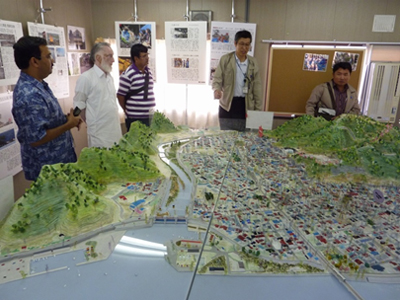 写真：復元された被災前の大槌町町方地区の模型を前に説明する東所長