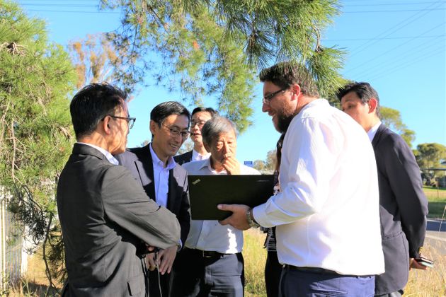 青空の下でオーストラリア・ニューサウスウェールズ州政府担当者と現地を視察をするUR職員の写真(外部ページへリンク。別ウィンドウで開きます)(別ウィンドウで開きます)
