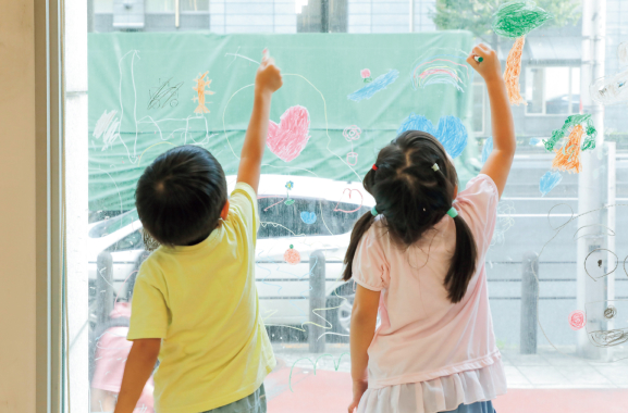 子どもたちが窓に絵を描いている写真