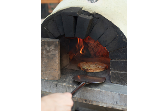 石窯でピザを焼いている写真