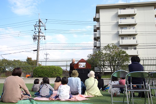 紙芝居を外で楽しむんでいる写真