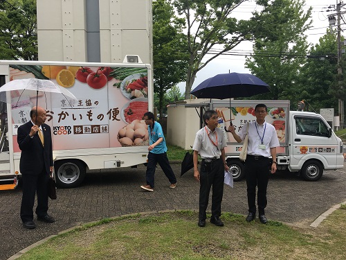 移動販売車の前に立つ、小石京都市社会福祉協議会会長（左）と中山京都生協移動店舗チーフ（右）の写真