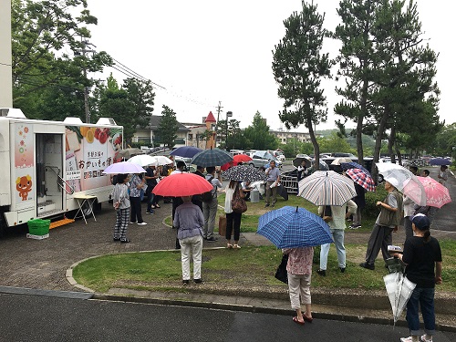 大勢のお客さまが移動販売車で買い物をしている写真