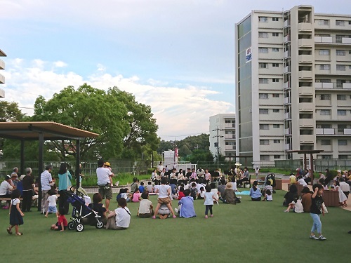 芝生に座りながら吹奏楽演奏会を聴いている写真