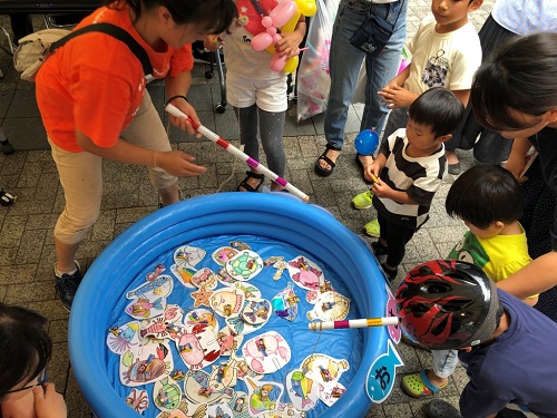 手作りのお魚にお菓子を付けて磁石で釣るゲームを楽しむ親子の写真