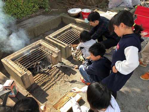 子どもたちが、かまどベンチで火起こし体験をしている写真