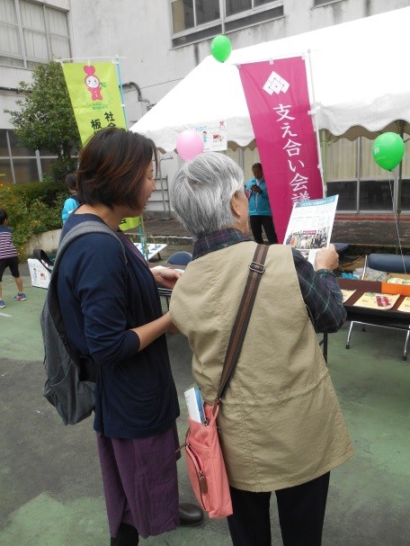 支え合い会議高島平の活動紹介ブース前でパンフレットを見る女性の写真