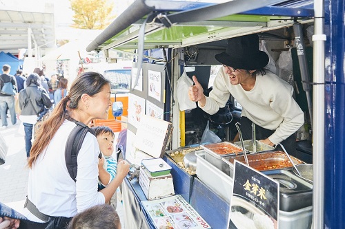 キッチンカーで買い物をする親子とキッチンカーの店主の写真