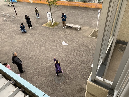 団地の広場で凧をあげて走る子どもの写真
