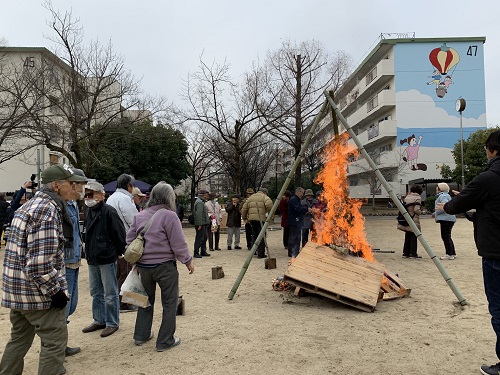 団地の広場で住民の方が集まってとんど焼きをしている写真