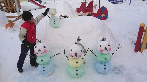 子供たちがかわいい雪だるまと作っている写真