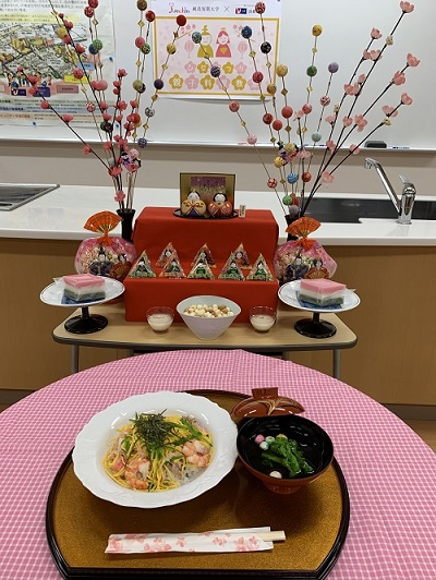 ひな壇のお雛様とちらし寿司、お吸い物がテーブルに乗っている写真