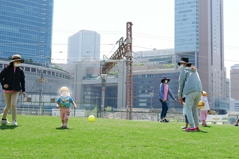うめきたの芝生広場の上で親子でボール遊びをしている写真