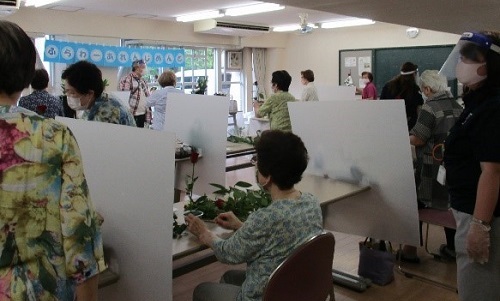 参加者がパーテーションが設置された部屋で花を活けている写真