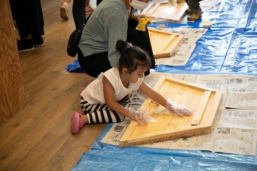 子どもが加工された机に板を張り付けている写真