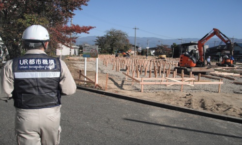 応急仮設住宅建設現場を視察するUR職員の写真