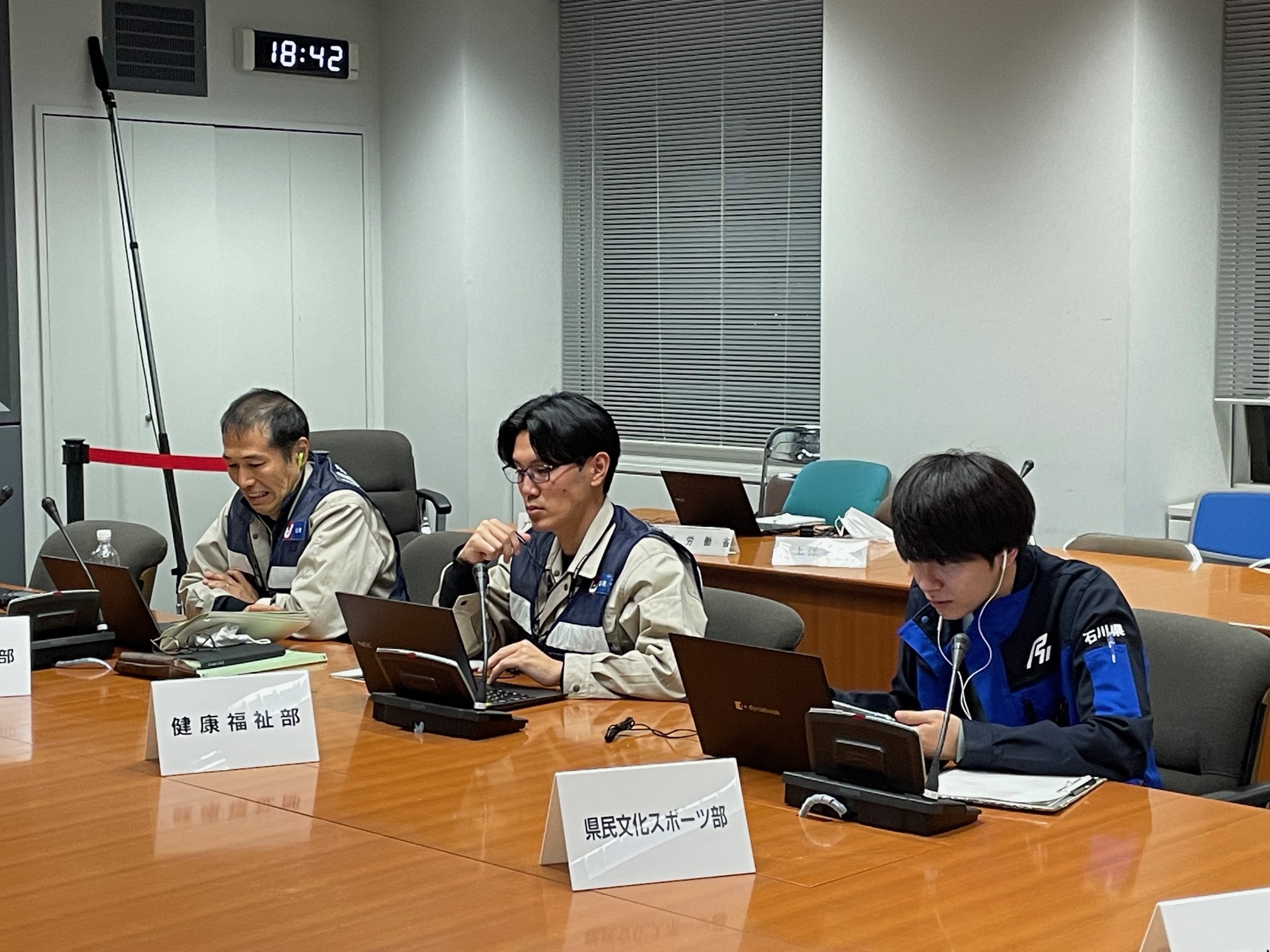 会議室で複数の担当者がノートパソコンを使って作業している様子。