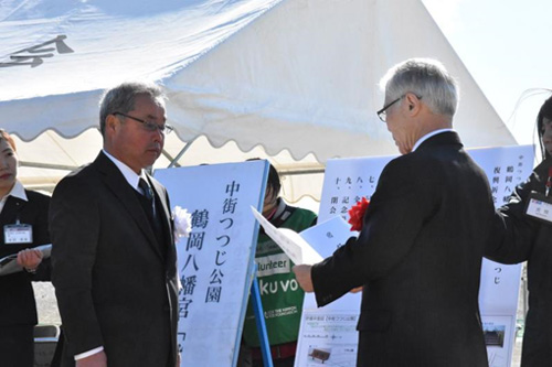 つつじを贈呈する𠮷田宮司(左)と受け取る鈴木区長