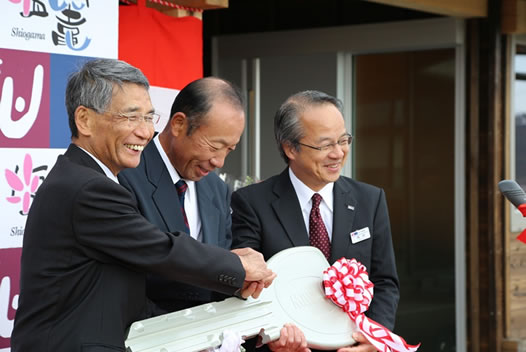 写真：朴島の鍵渡し式で固く握手をする佐藤市長（左）、入居者代表（中央）とUR稲垣宮城・福島震災復興支援本部長（右）