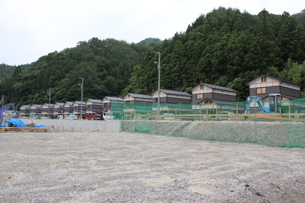 写真：寺野臼澤団地の様子。奥の２階建ての建物が災害公営住宅で、手前の盛土部分が戸建住宅用地