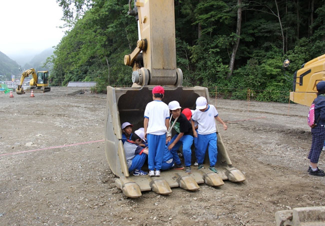 写真：バックホウのバケットに入ってみる小学生