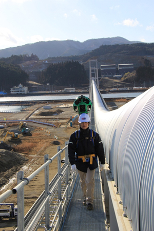 ベルトコンベアーの横を渡る職員の写真