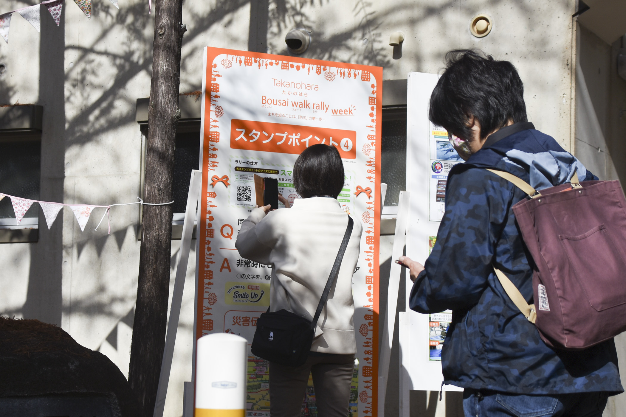 ウォークラリーのスタンプポイントをスマートフォンで撮影する住民の方